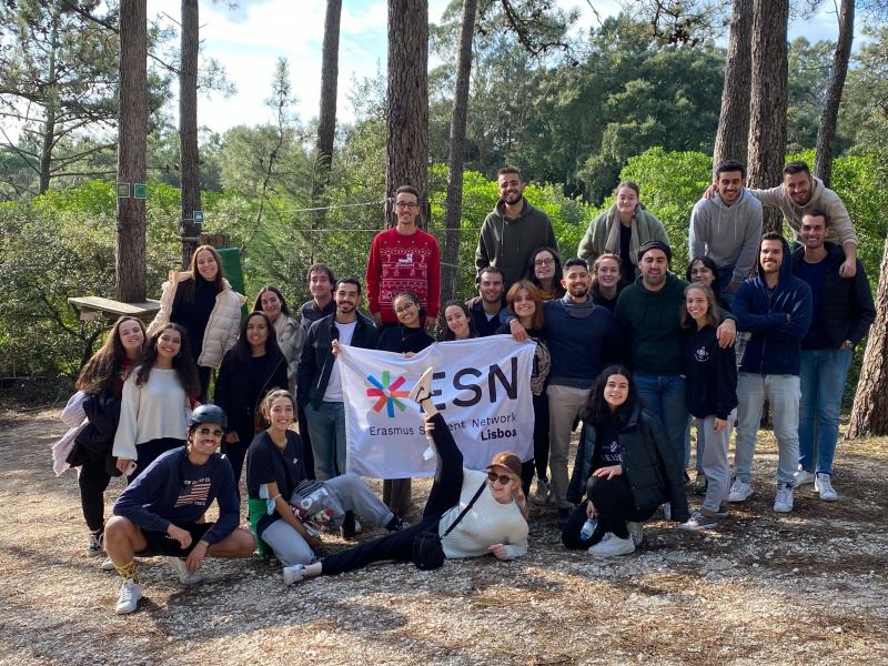 The ESN Lisboa Team of 2021/2022 in a forest, beaming and holding their beloved ESN Lisboa flag :)